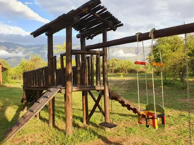 a wooden playground with a swing and a slide at La Maína Cabañas in San Javier