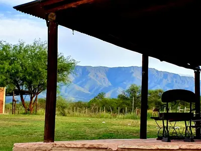 a table and chair in a pavilion with mountains in the background at La Maína Cabañas in San Javier