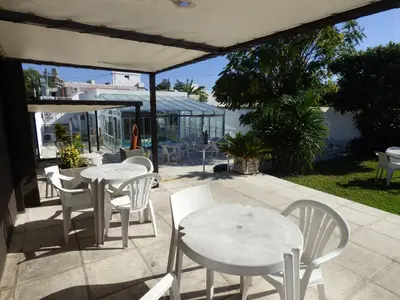 two tables and white chairs on a patio at Hotel Linz in Villa Carlos Paz