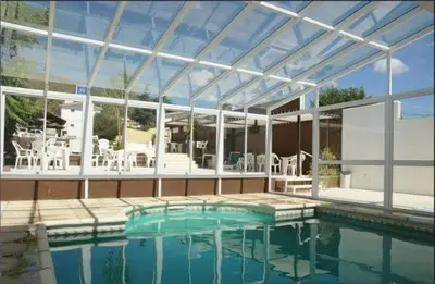 a swimming pool with a large building with a large glass at Hotel Linz in Villa Carlos Paz