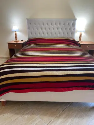 a bed with a striped comforter and two night stands at Carlos Paz Departamentos in Villa Carlos Paz