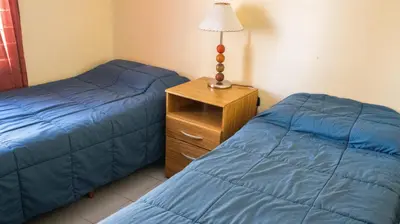 a bedroom with two beds and a lamp on a night stand at Carlos Paz Departamentos in Villa Carlos Paz