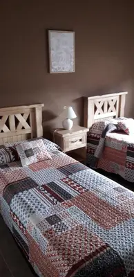 a bedroom with two beds and a table with a lamp at Cabañas Ayres de Sierra in Los Reartes