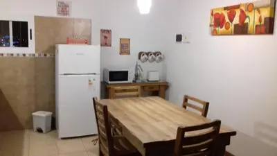 a kitchen with a table and a white refrigerator at Cabañas Ayres de Sierra in Los Reartes