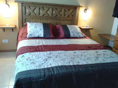 a bedroom with a large bed with a wooden headboard at Cabañas Ayres de Sierra in Los Reartes