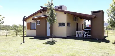 a small house with a tree in front of it at Cabañas Ayres de Sierra in Los Reartes