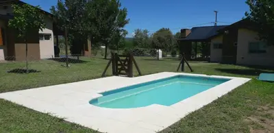 a swimming pool in a yard with a playground at Cabañas Ayres de Sierra in Los Reartes
