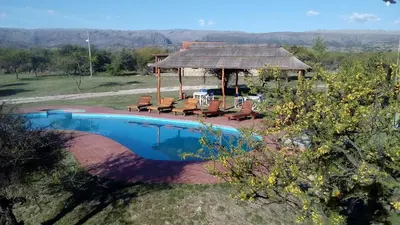 a swimming pool with chairs and a gazebo at Alto Valle Cabañas de Montaña in Mina Clavero