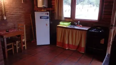 a kitchen with a refrigerator and a table and a sink at Alto Valle Cabañas de Montaña in Mina Clavero
