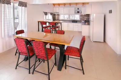 a kitchen with a wooden table and red chairs at La Faustina Casas de Campo in Villa General Belgrano