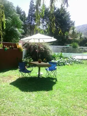 a table and two chairs under an umbrella in a yard at Villa Verde Posada in Bialet Massé