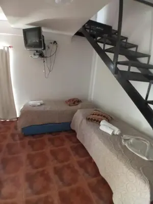 a room with two beds and a tv and a staircase at Nuestro Rinconcito in Villa Cura Brochero