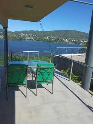 a table and chairs on a balcony with a view of the water at lacasonavistalago in Villa Carlos Paz