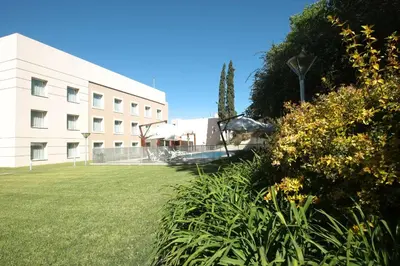 a white building with a grassy yard next to a building at Howard Johnson Rio Cuarto Hotel y Casino in Río Cuarto