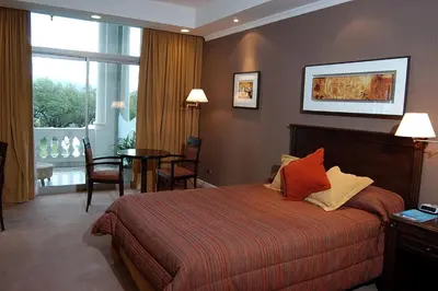 a hotel room with a bed and a table with chairs at Howard Johnson Sierras Hotel y Casino Alta Gracia in Alta Gracia