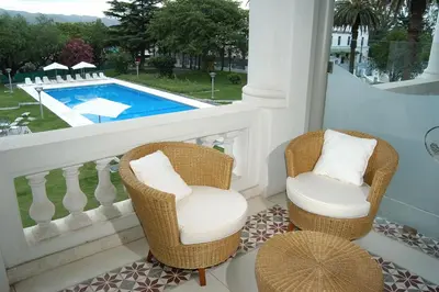 a balcony with two chairs and a swimming pool at Howard Johnson Sierras Hotel y Casino Alta Gracia in Alta Gracia