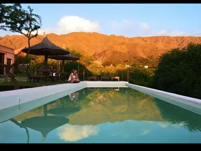 a woman is sitting next to a swimming pool at Los Remolinos in Merlo