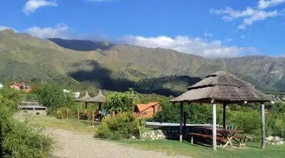 a hut with a table and a bench and mountains at Los Remolinos in Merlo