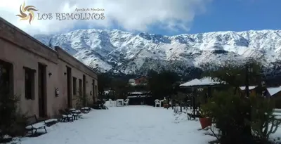 a building with snow covered mountains in the background at Los Remolinos in Merlo