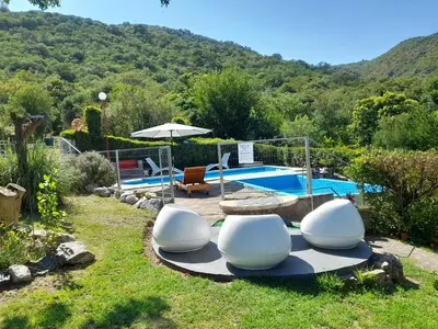 a pool with two white chairs and an umbrella at Sierras Del Sol in Villa Carlos Paz