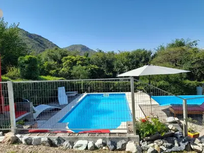 a swimming pool with an umbrella next to a fence at Sierras Del Sol in Villa Carlos Paz