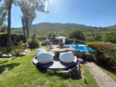 a patio with two white chairs and a pool at Sierras Del Sol in Villa Carlos Paz