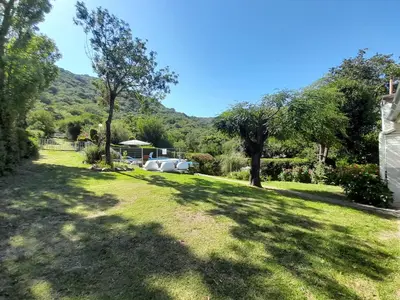 a grassy yard with trees and a house at Sierras Del Sol in Villa Carlos Paz