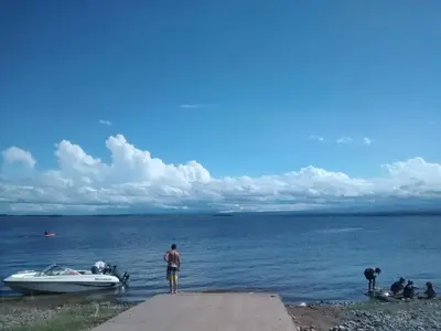 a man standing next to a boat on the shore at 2 PAX Departamentos in Villa Rumipal