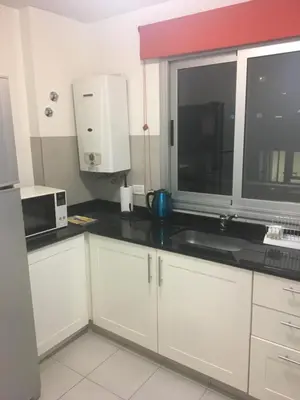 a kitchen with white cabinets and a sink and a window at Departamentos Mediterraneo in Cordoba