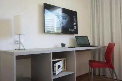 a desk with a laptop and a tv on a wall at Buen Pastor Capuchinos in Cordoba