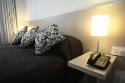 a hotel room with a bed with a telephone and pillows at Buen Pastor Capuchinos in Cordoba