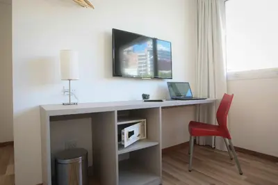 a desk with a computer and a red chair at Buen Pastor Capuchinos in Cordoba