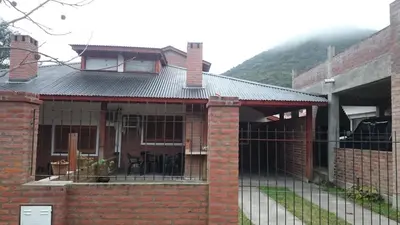 a brick house with a fence in front of it at Cabañas Simpson in Santa Rosa de Calamuchita