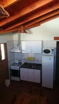 a kitchen with white cabinets and a stove top oven at Cabañas Simpson in Santa Rosa de Calamuchita