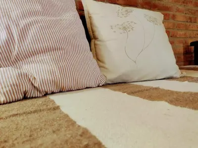 a bed with a pillow next to a brick wall at El Chañar in Villa General Belgrano