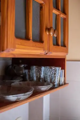 a wooden cabinet with bowls and plates on a shelf at El Chañar in Villa General Belgrano