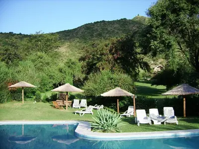 a pool with chairs and umbrellas next to at Cabañas Mirasoles in Villa General Belgrano