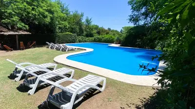 a group of white chairs sitting next to a swimming pool at Cabañas Mirasoles in Villa General Belgrano