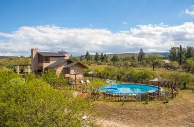 a swimming pool in a yard with a house at Complejo San Pio in Villa Icho Cruz