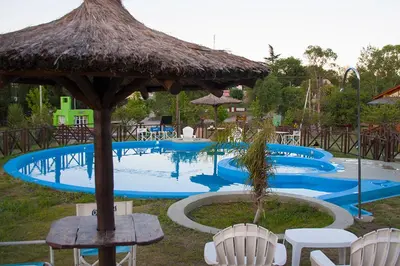 a large swimming pool with chairs and a straw umbrella at Complejo San Pio in Villa Icho Cruz
