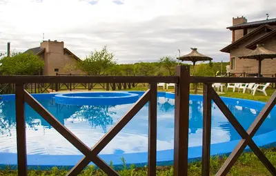 a fence with a blue pool in front of a house at Complejo San Pio in Villa Icho Cruz