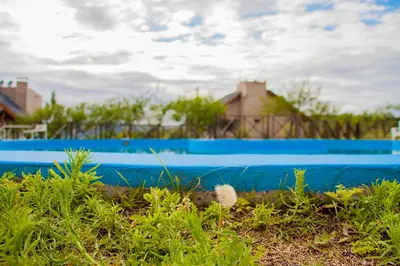 a blue swimming pool in front of a house at Complejo San Pio in Villa Icho Cruz