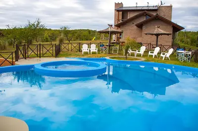 a large blue pool with chairs and a house at Complejo San Pio in Villa Icho Cruz