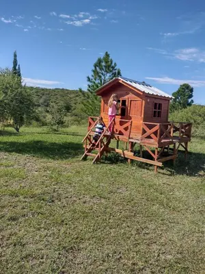 a woman standing outside of a tiny house at Complejo San Pio in Villa Icho Cruz