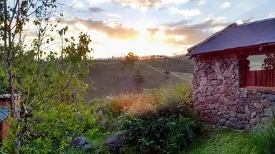 a stone building in a field with the sunset in the background at Serranias Del Tabaquillo in San Miguel de los Rios