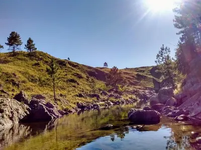 a river with rocks and the sun in the sky at Serranias Del Tabaquillo in San Miguel de los Rios
