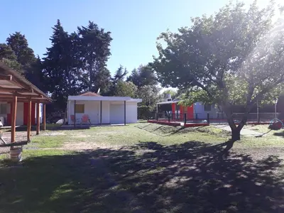 a park with a tree and a building at Complejo Leon in Villa Rumipal