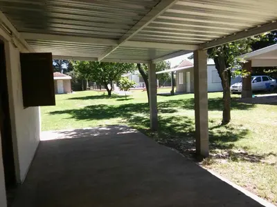 a covered walkway leading to a yard with trees at Complejo Leon in Villa Rumipal