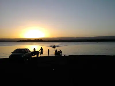 a group of people on the beach at sunset at Complejo Leon in Villa Rumipal