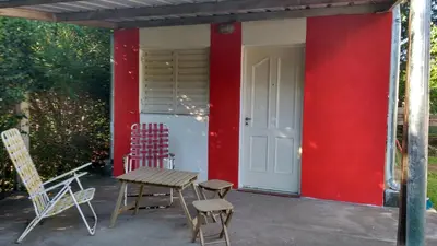 a patio with chairs and a table and a red wall at Complejo Leon in Villa Rumipal